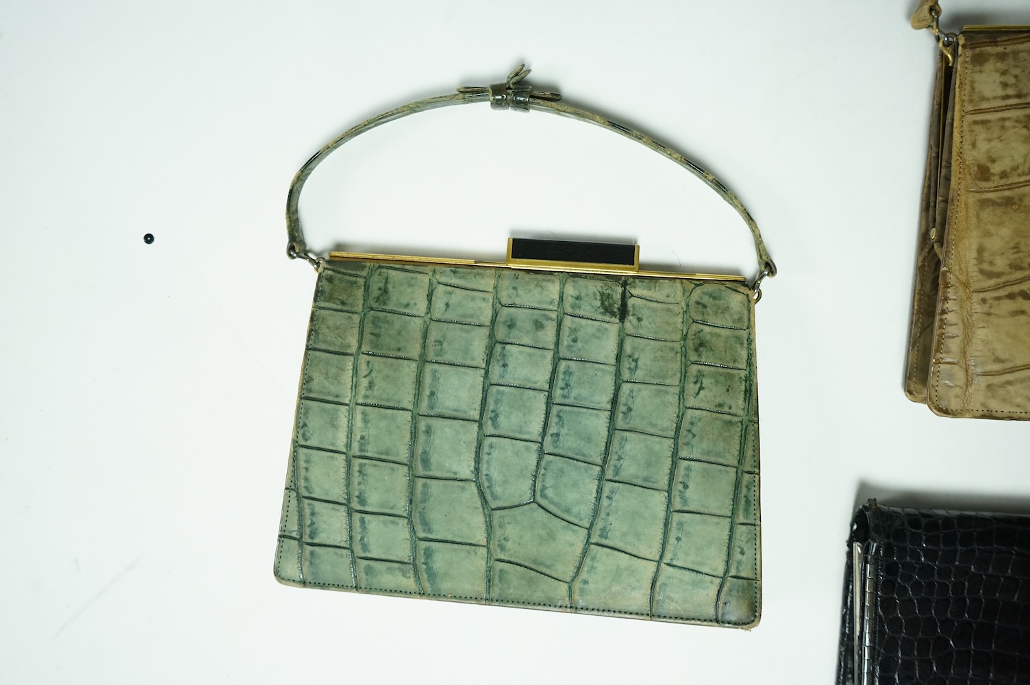 Three stylish Art Deco ladies handbags. A black crocodile clutch bag with an MMW monogram and silver mounted edge and two smaller handbags, one green the other brown, both faux crocodile with stylish bakelite clasps. Clu